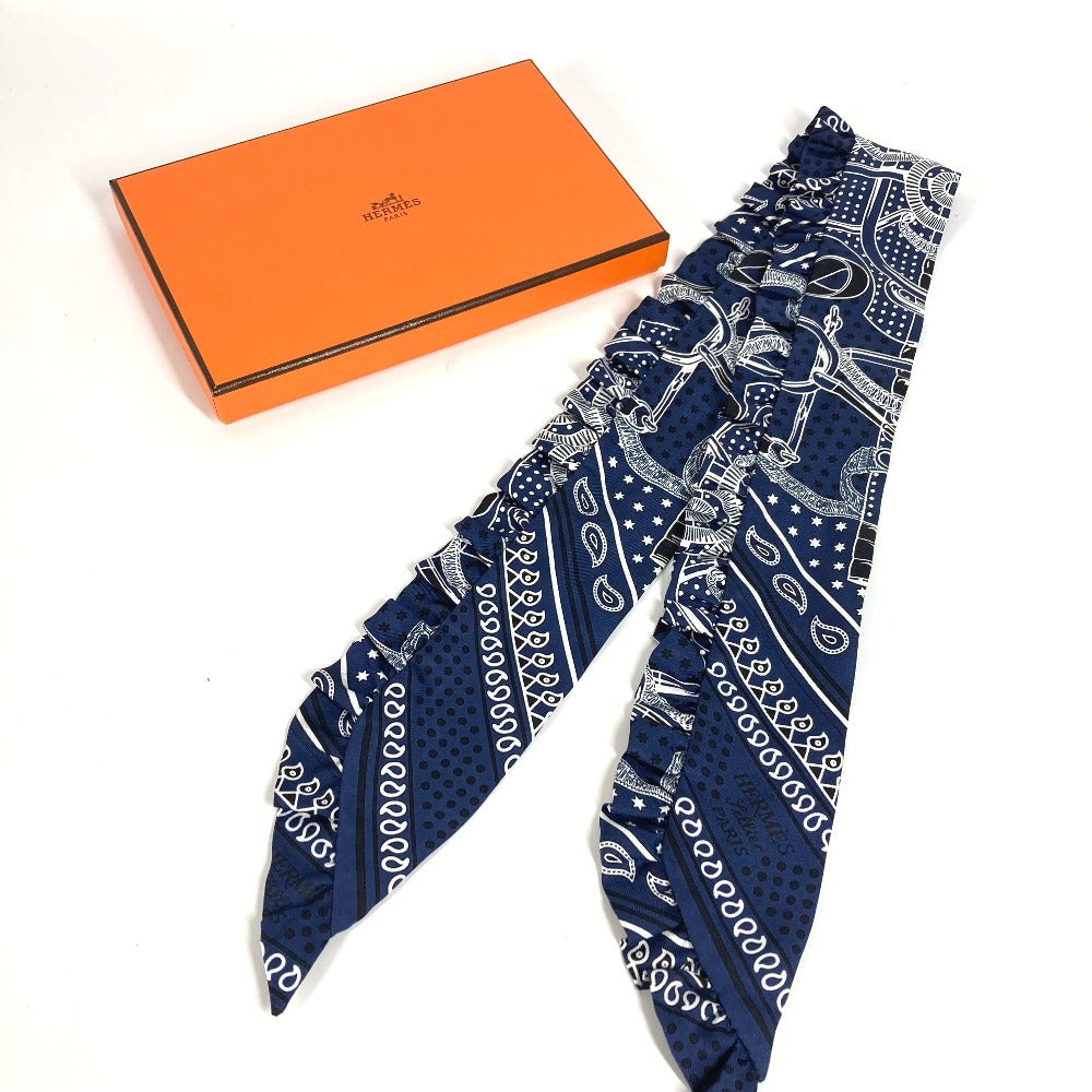 HERMES Apron d'Or, a silk scarf with a ruffled twilly lining, available in Marine Foncé, black, white, and blue.